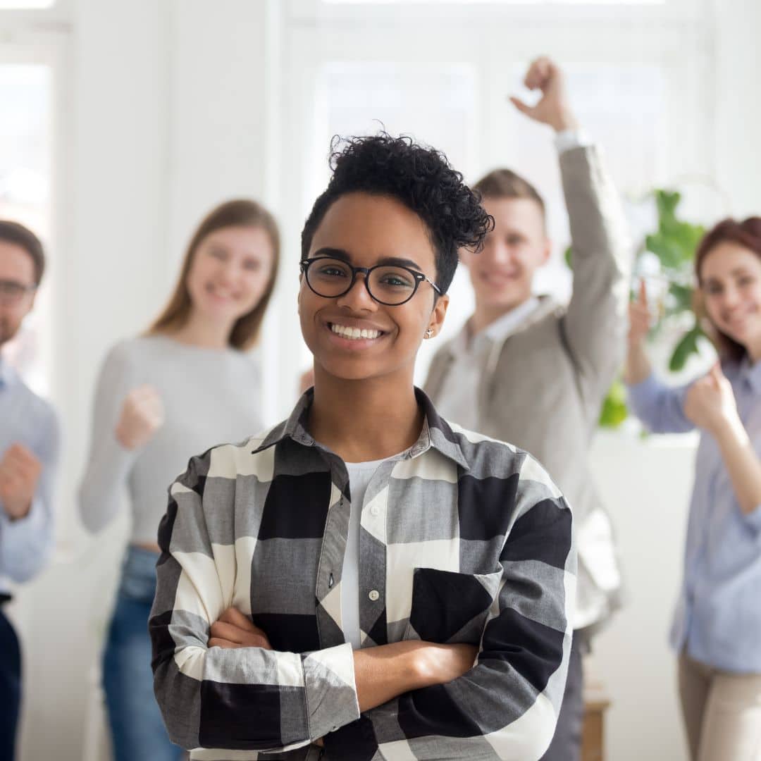 Business leader standing confidently in front of her team of cheering employees